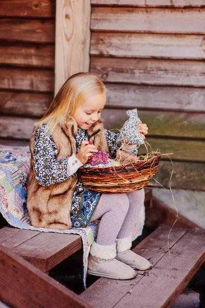 Adorable happy child girl with decorations for easter at wooden country house