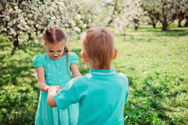 Happy brother and sister in blooming garden