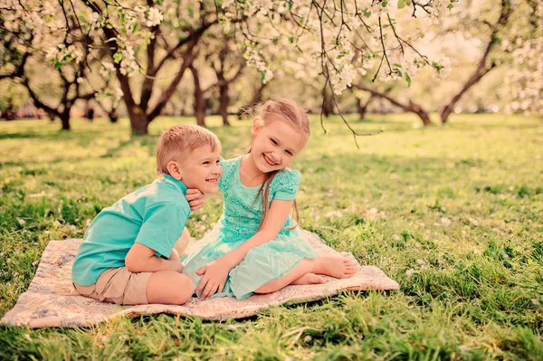 Happy brother and sister in blooming garden