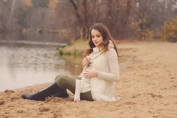 Happy beautiful pregnant woman on cozy outdoor walk on river side, soft warm toned