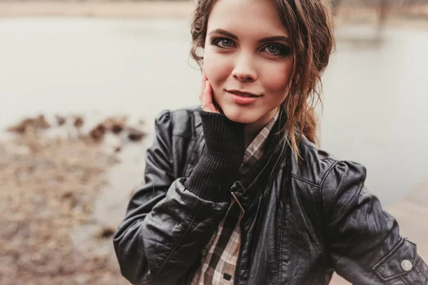 Portrait of adorable young woman in leather jacket walking outdoor on countryside