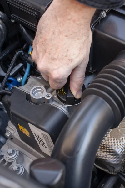 Hand that controls the oil cap in a latest generation car engine