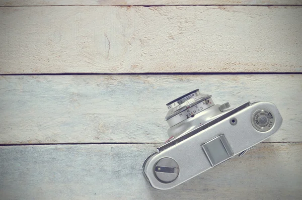 Retro photo camera on a wooden background, top view. Vintage scene on a white wooden table