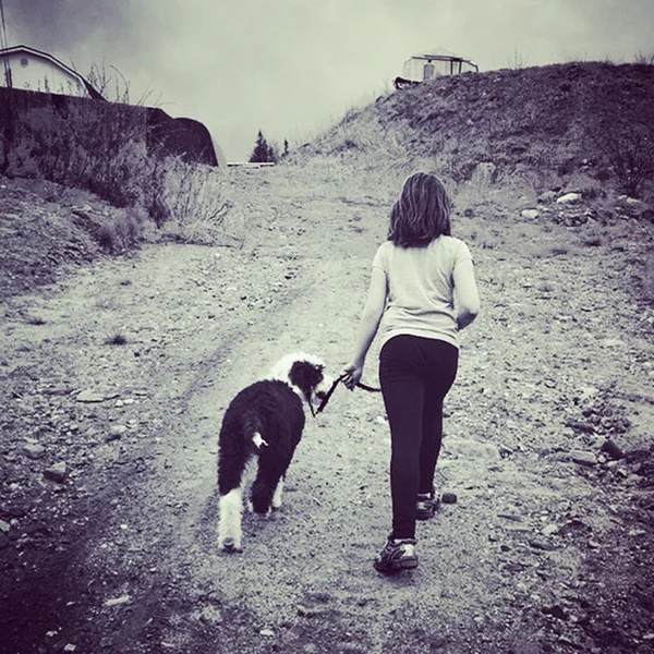 Sweet instagram of girl walking her dog up a hill  in black and