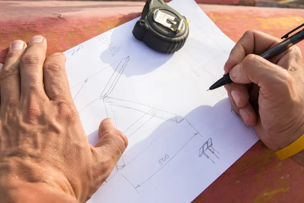 Closeup photo of drawing and carpenters hands who is going to make design