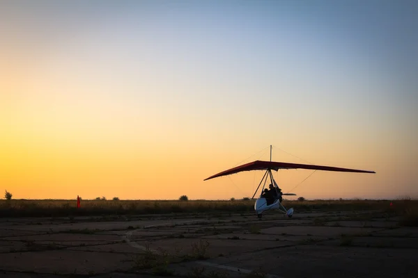 Hang-gliding, standing at dawn on the runway