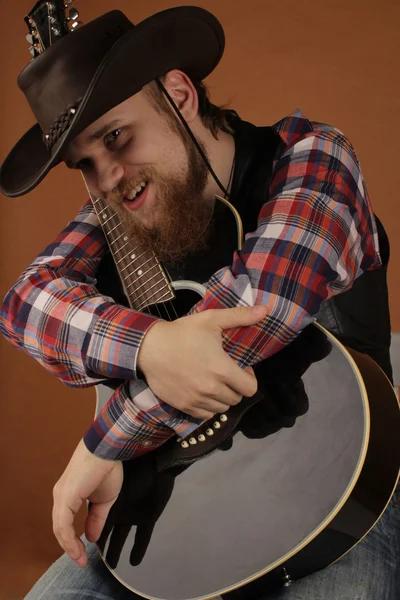Portrait of the young man of the cowboy with a guitar