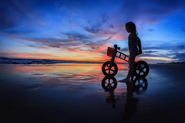Child with run bike on sunset beach