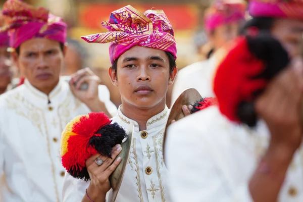BALI, INDONESIA - JUNE 13, 2015: Young musician man of traditional Balinese people orchestra Gamelan in Balinese style male costume playing ethnic music on ceremony procession at Art and Culture Festival.
