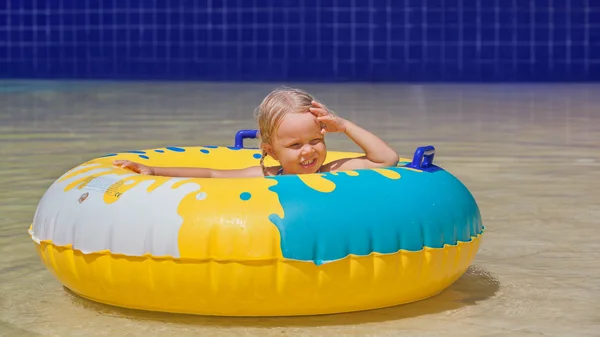 Child sunbathing, swim with inflatable toy in swimming pool
