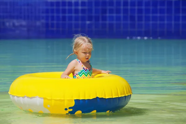 Funny portrait of cheerful baby girl swimming in water park