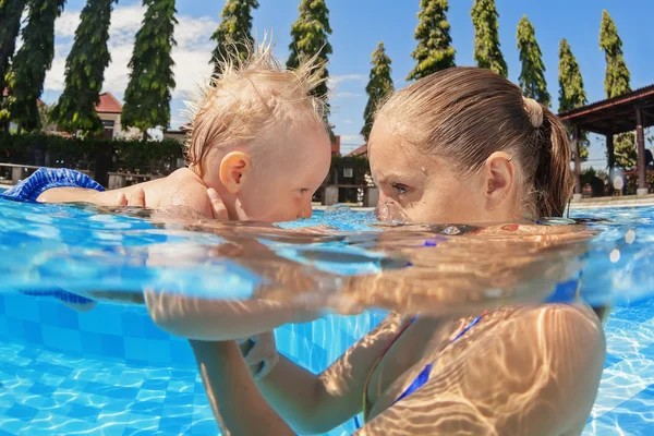 Little baby boy swimming in outdoor pool with mother