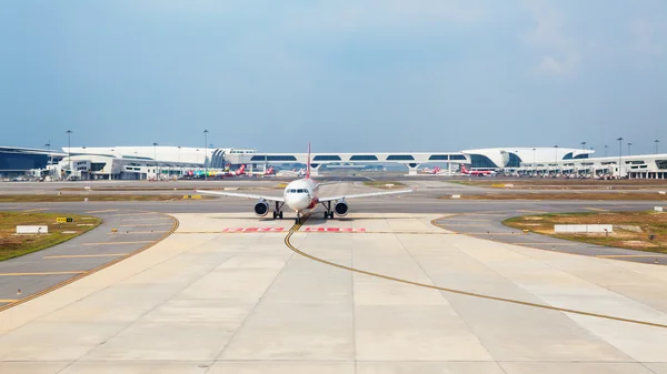 Air asia low cost airline aircraft on the background of transit passenger terminal building waiting for take off in malaysian international airport KLIA 2