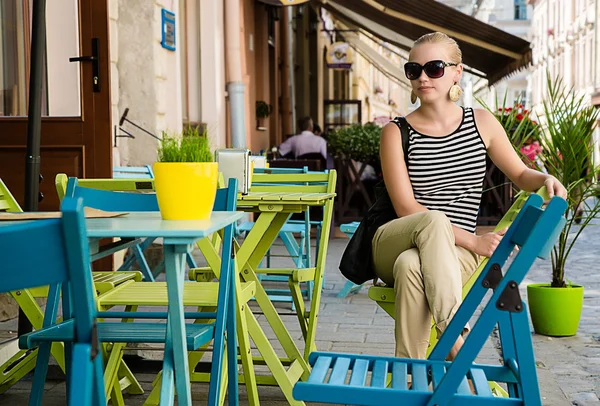 Beautiful young woman sitting  alone in  the street cafe