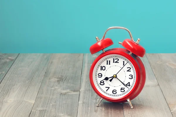 Red retro alarm clock on a wooden table.