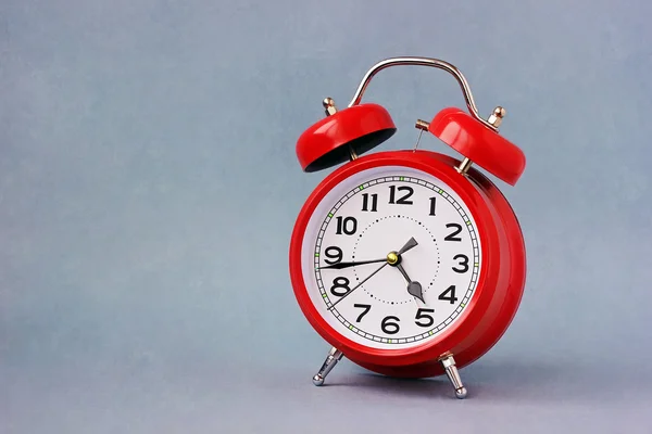 Red retro alarm clock on a blue background.