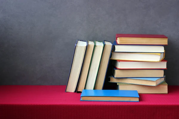 Stack of books on the table with a red tablecloth.