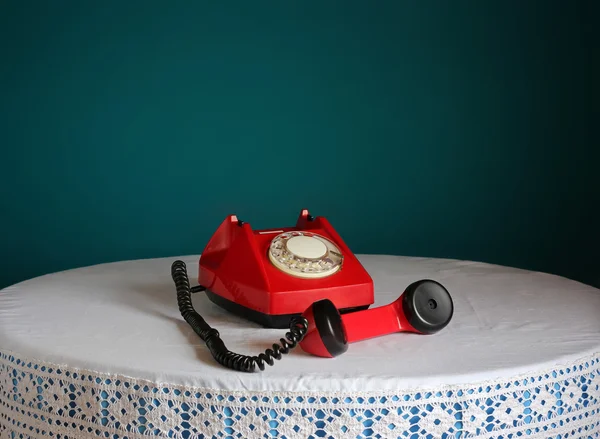 Red retro rotary telephone on a round table.