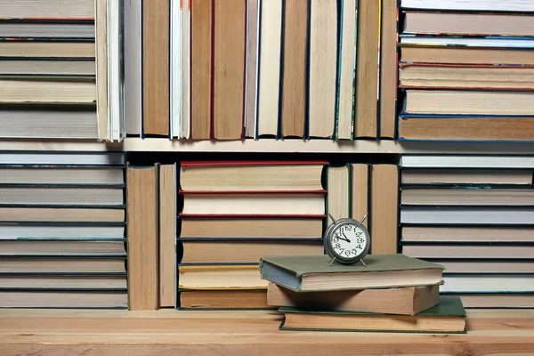 Retro alarm clock on a background of books. Book background.