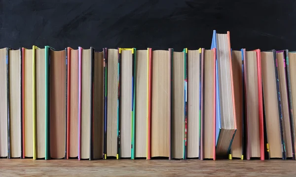 Books on the shelf in the background of a school blackboard.