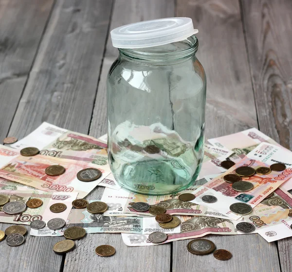 Empty glass jar and Russian money on the wooden floor.