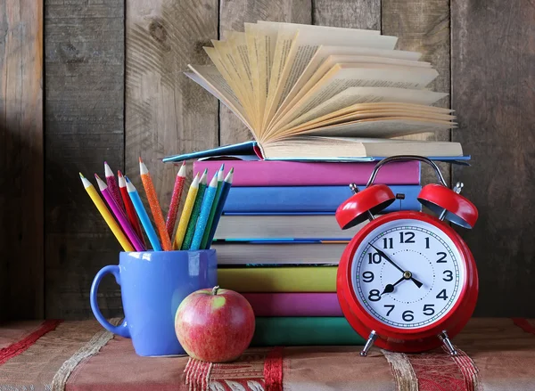 Back to school. Books, colored pencils and alarm clock.