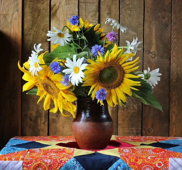 Still life with a bouquet of sunflowers, camomiles and cornflowers. Sunflowers.