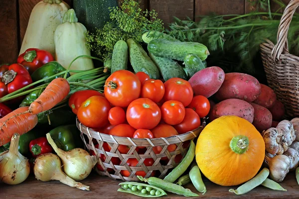 Still life with vegetables: tomato, carrots, pepper, potatoes, onions, vegetable marrow, garlic, cucumber, pumpkin, fennel, peas.