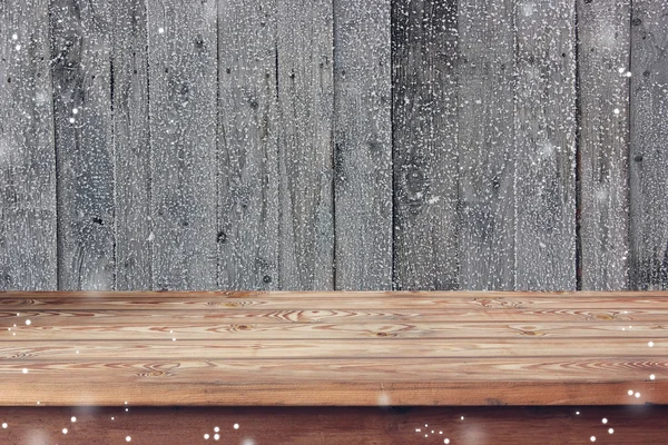 Empty wooden table against a wall from the boards covered with h