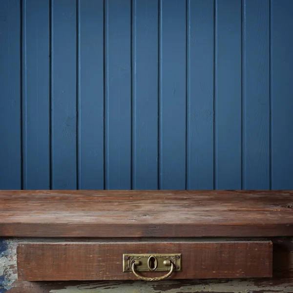 Empty wooden table against a wall from the boards painted in blu