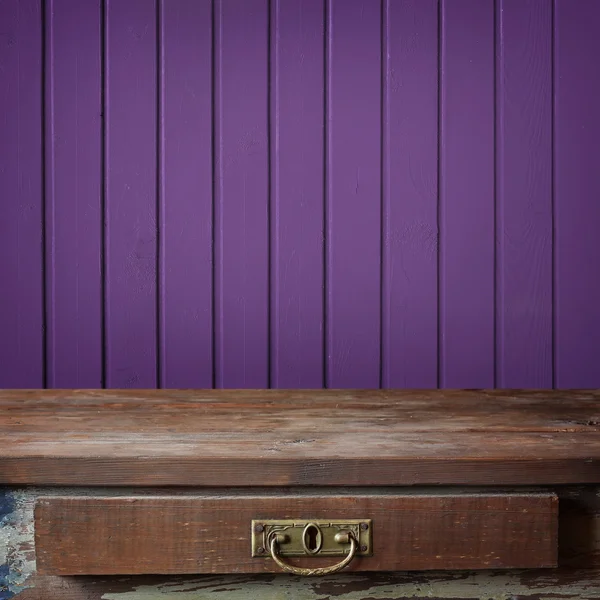 Empty wooden table against a wall from the boards painted in vio