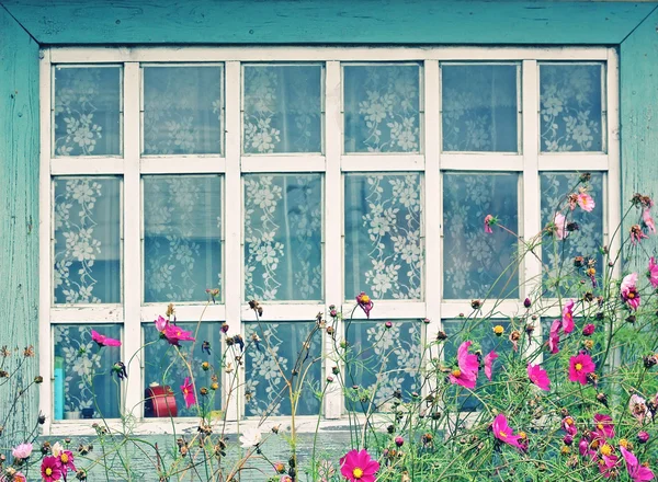 Window of a country house with flowers in the foreground