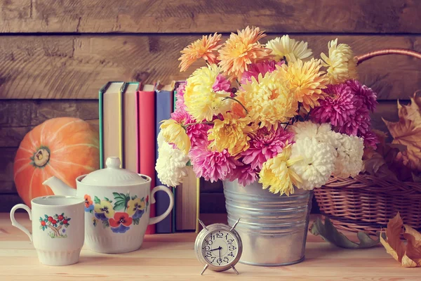 Still life with a bouquet of chrysanthemums, an alarm clock, boo