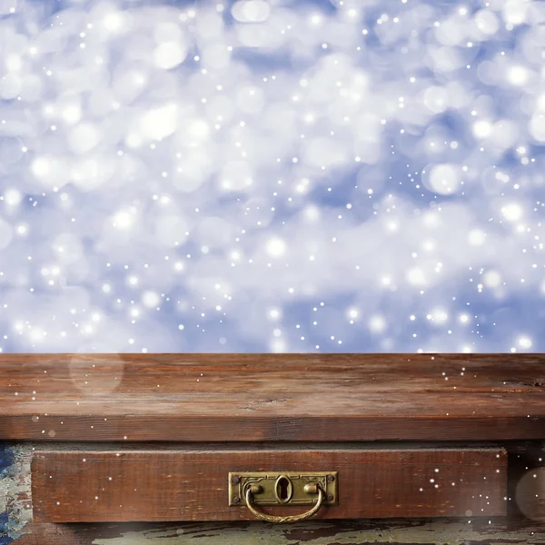 Empty wooden table on a blue background with the falling snow.