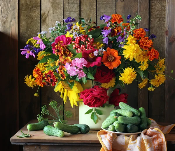 Still life with flowers in a can and cucumbers.