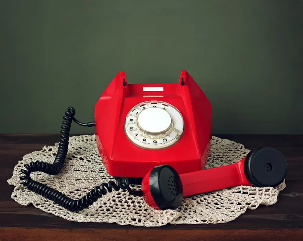 Red retro rotary phone on a lacy napkin.