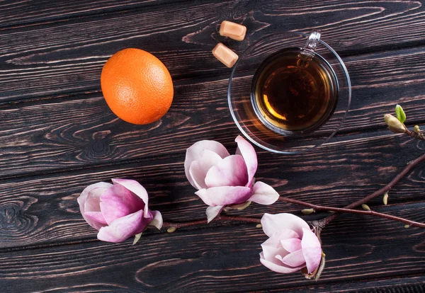 Cup of black tea and flower magnolia on wooden boards.