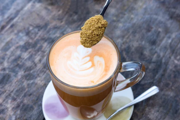 Soft focus and blur tea cup and teaspoon. Pouring natural sugar