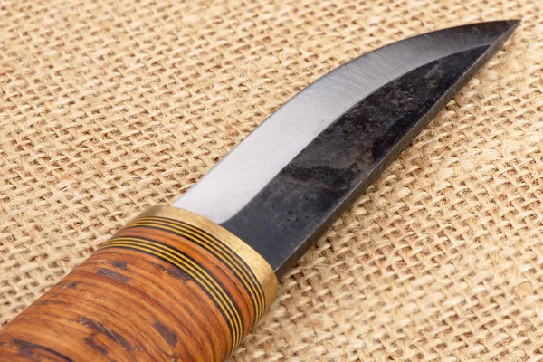 Traditional handmade Finnish knife with the wooden handle over an old sack background.