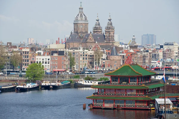 View to the city of Amsterdam with canal, historic buildings and basilica of Saint Nicholas in Amsterdam, Netherlands.