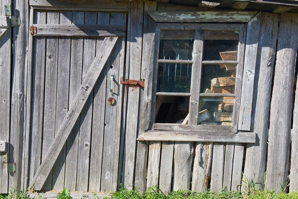 Old wooden barn with a closed door and broken window.