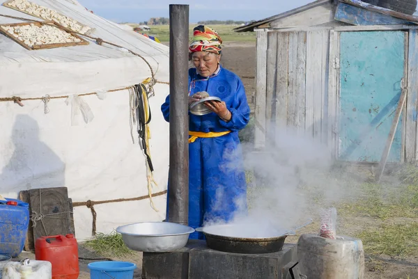 Woman cooks in front of the yurt entrance circa Harhorin, Mongolia.