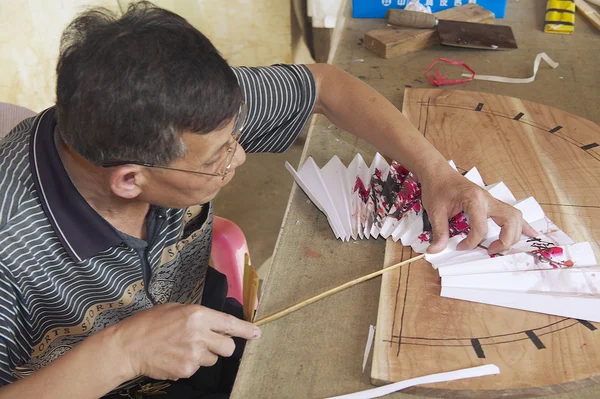 Man produces traditional Chinese fanin Yangshuo, China.