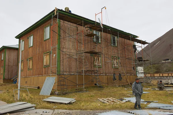 People repair building in the abandoned Russian arctic settlement Pyramiden, Norway.
