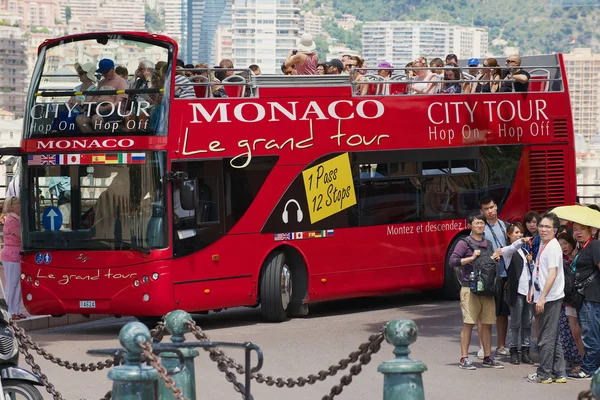 People enjoy sightseeing tour on the red Monaco city tour bus in Monaco.