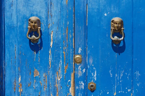 Blue painted aged wooden door with old bronze handles and locks in Rimini, Italy.