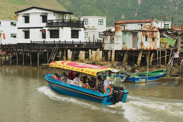Tourists enjoy boat trip at the Tai O fishermen village with stilt houses in Hong Kong, China. Tai O is a famous tourist destination in Hong Kong.