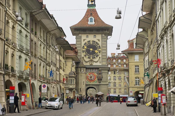 People walk by the street with the historic Bern Clock tower at the background in Bern, Switzerland.