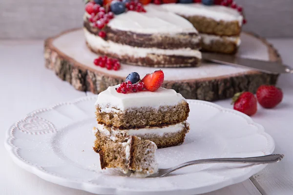 Cut piece of home made Earl Grey naked cake with cream cheese and berries