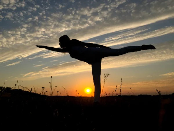 Woman balancing in one leg at sunset.